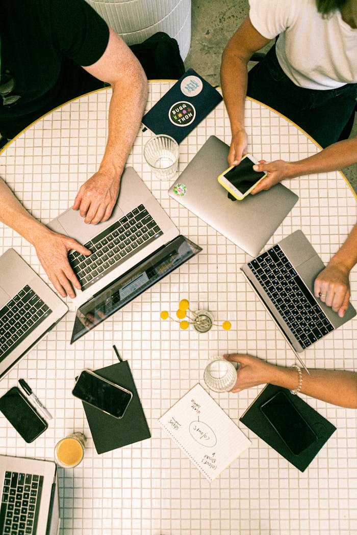 creative Top view of a team collaborating with laptops, phones, and notes in a modern office.